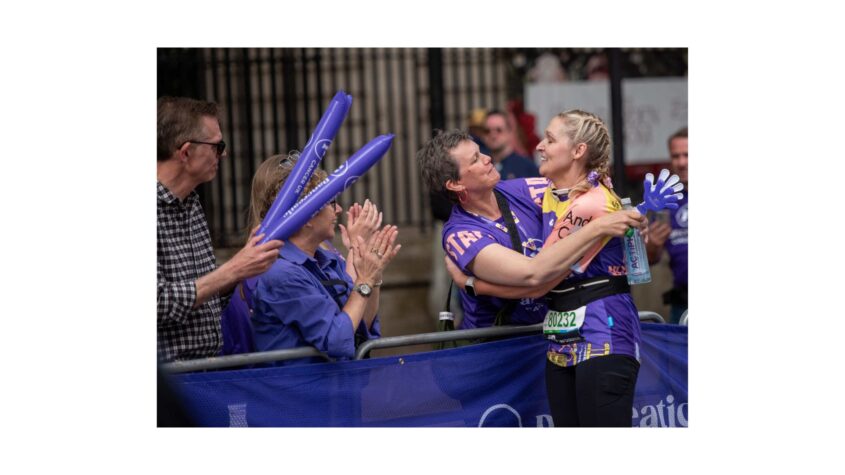Woman taking break from running marathon hugging a supporter