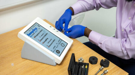 A person wearing gloves assembles a breath testing device