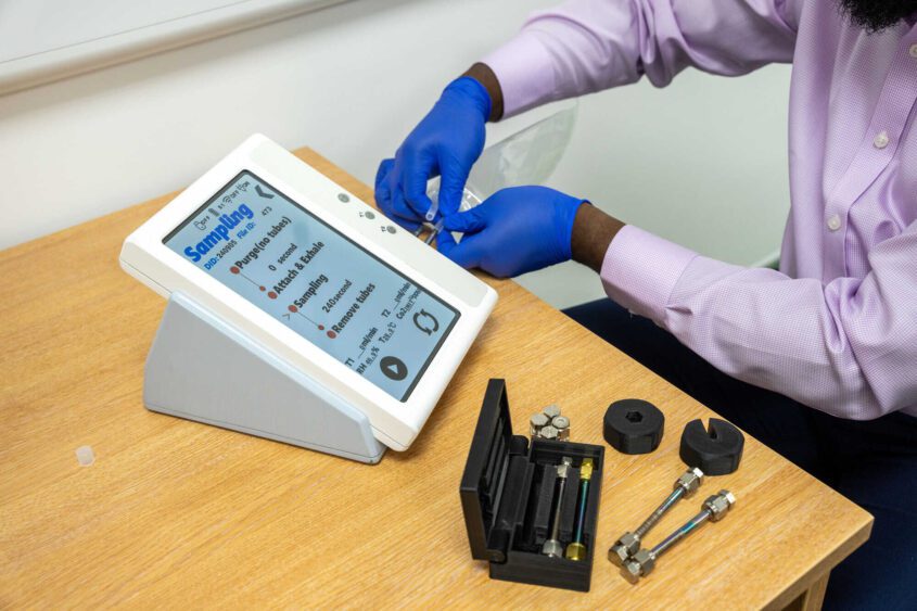 A person wearing gloves assembles a breath testing device