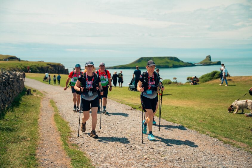 Group of people walking along the Gower Peninsula coastline