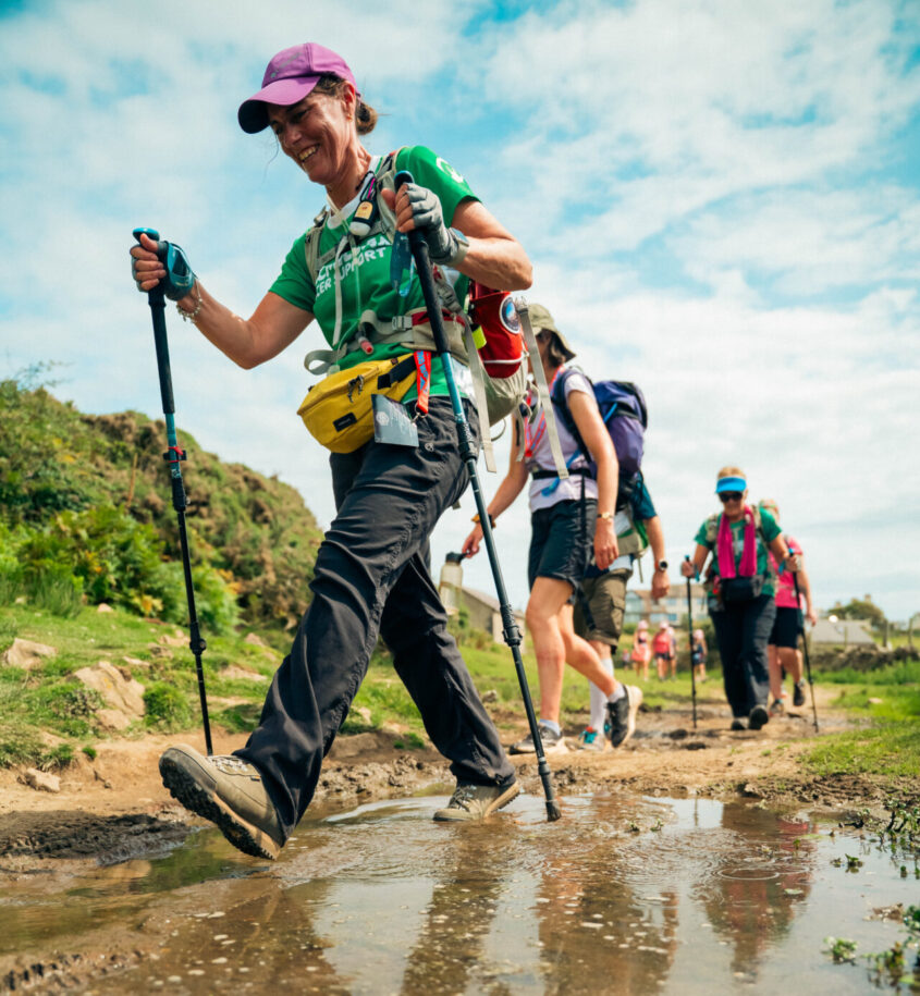 Close up of walkers in the Peak District walking through a puddle with their walking sticks