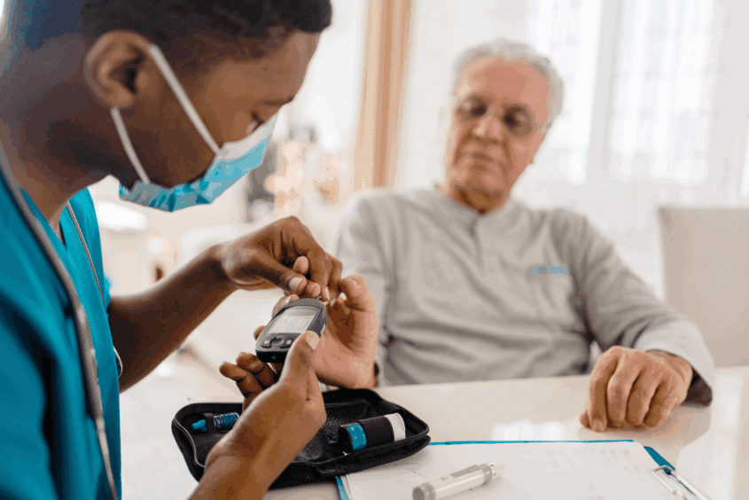 A health professional measuring the blood glucose level of a patient