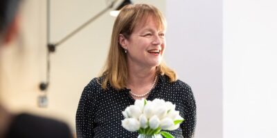 Professor Alice Gast staring off camera holding white flowers in their hands