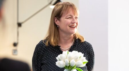 Professor Alice Gast staring off camera holding white flowers in their hands
