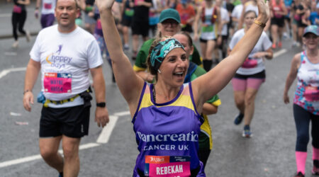 woman with her arms in the air running in a pancreatic cancer top for the great north run