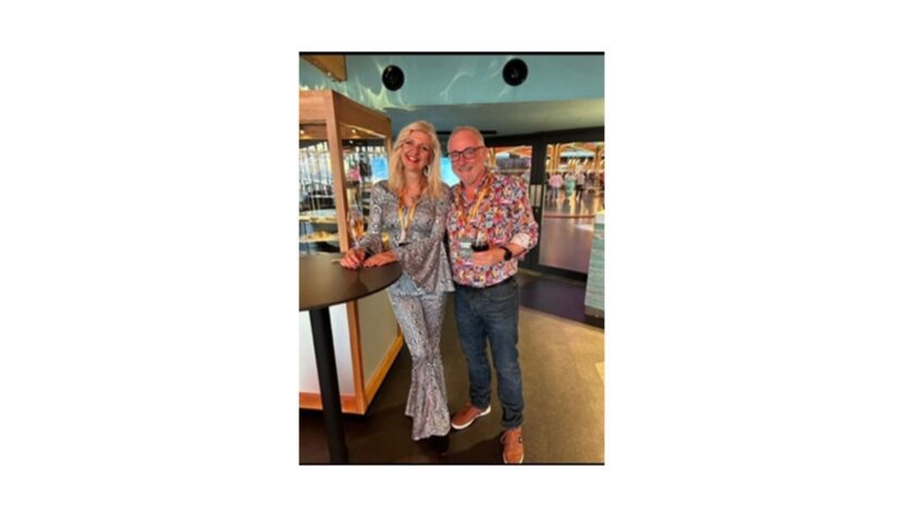 Man and woman standing in a restaurant or bar both smiling to camera