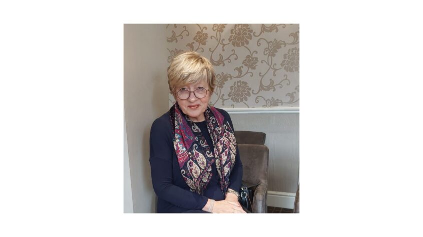 Middle age lady, dressed smartly sitting at a table in a restaurant or hotel.