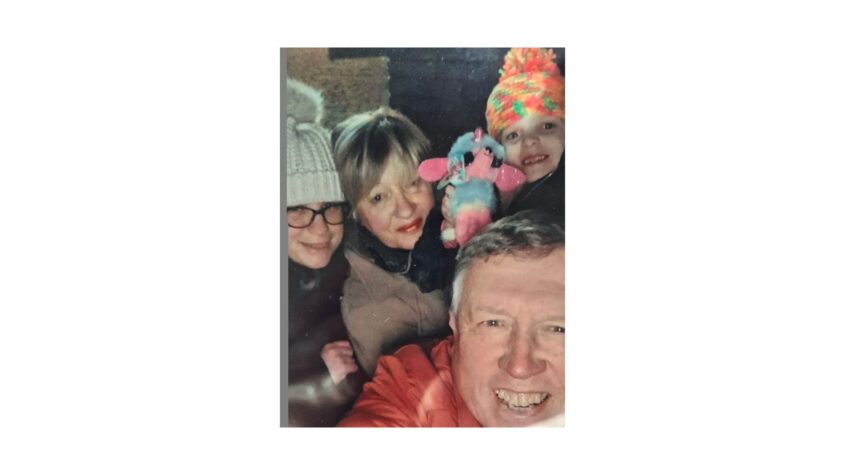 Middle age lady and man with two young children in a group family selfie, all wearing warm cosy clothes
