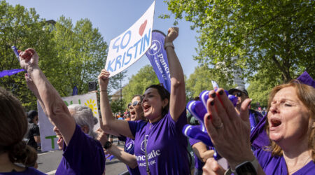 A group of volunteers cheering at a cheer point, holding up posters