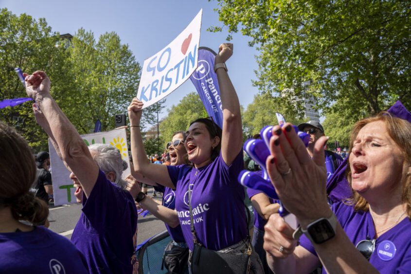 A group of volunteers cheering at a cheer point, holding up posters