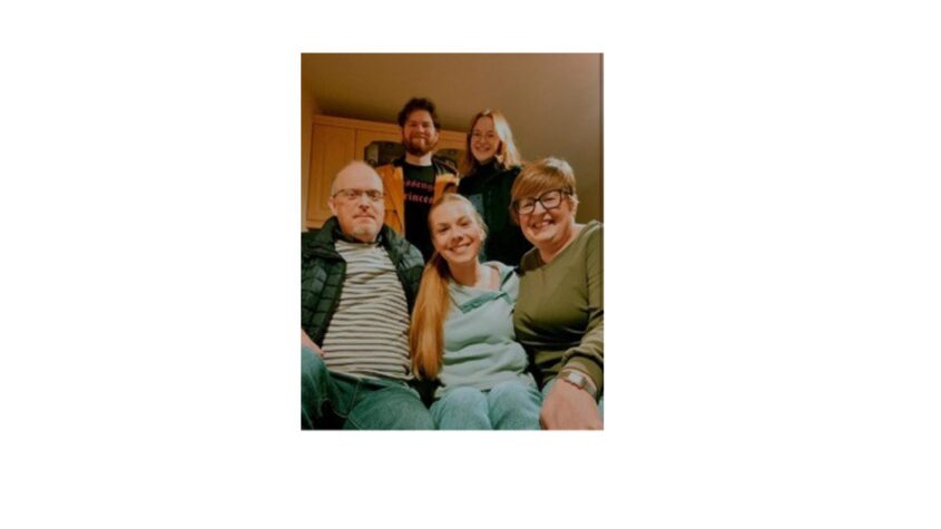 family huddled close together, all smiling to camera