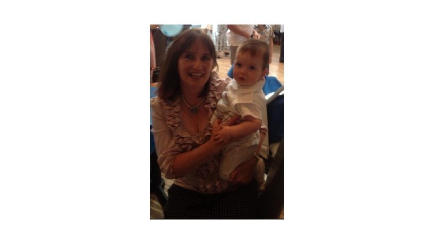 Middle age lady holding a young toddler and smiling to camera