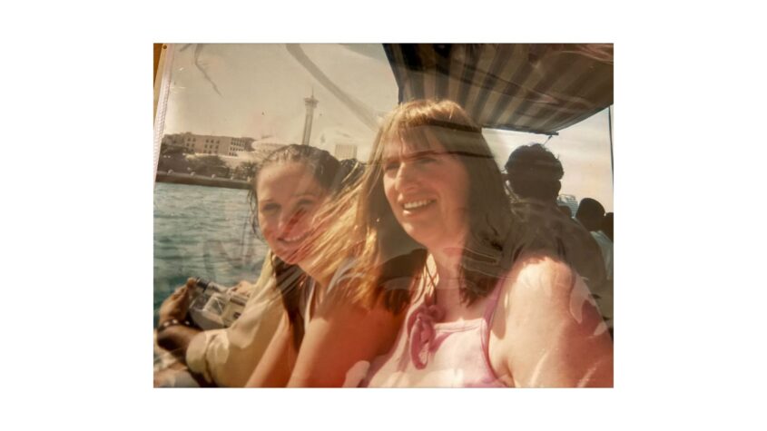 An old photo of a young woman and her daughter on a boat. both wearing summery clothes and smiling