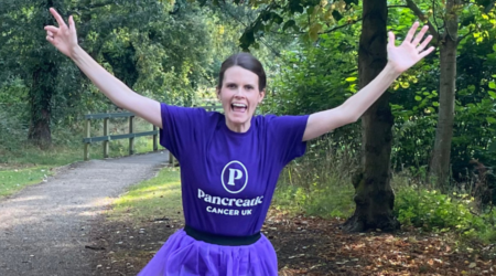 Person running in a pancreatic cancer uk top through a wood