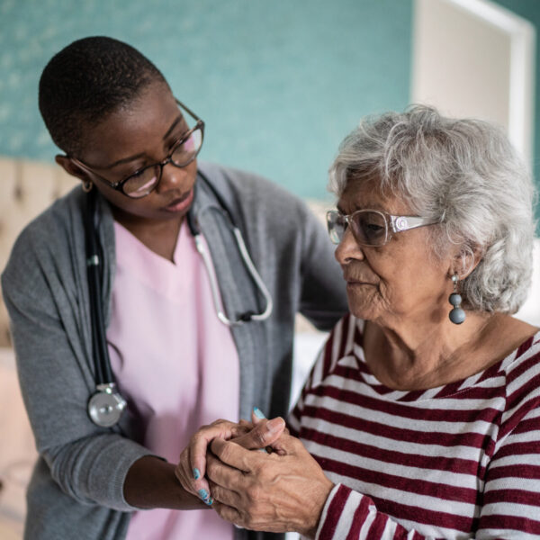 Home caregiver helping a senior woman standing in the bedroom