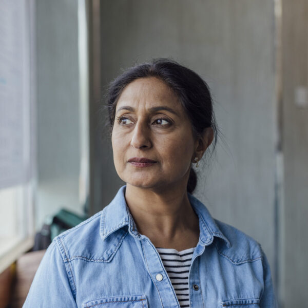 Close up front view of a mature female customer sitting waiting for her order in a local family run pizza shop in North Yorkshire, England. She is wearing casual clothing she is looking away out the window.