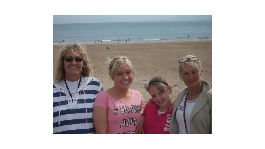 2 older woman and 2 younger women in family pic, standing in front of a beach