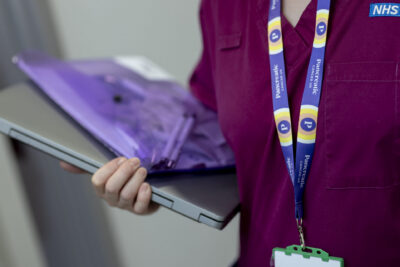 A health professional holding a laptop