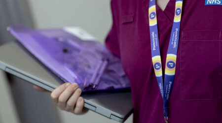 A health professional holding a laptop
