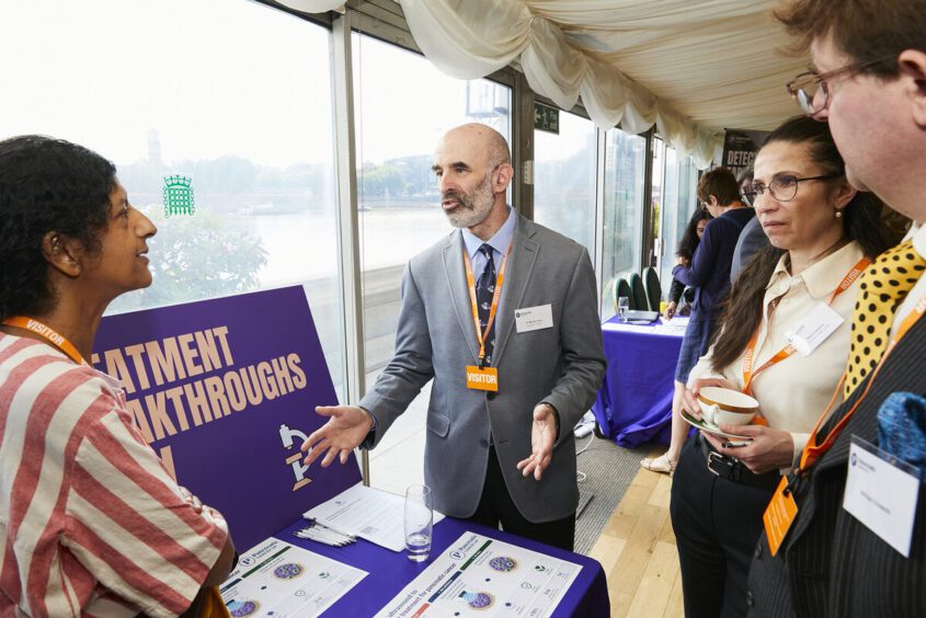 Dr Michael Gray standing next to a table with documents about his research.
