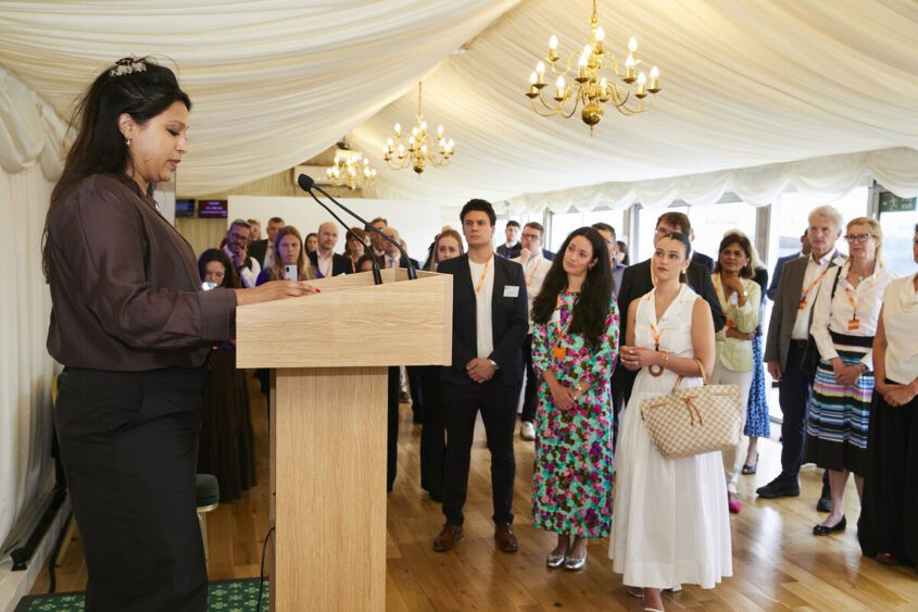 Picture of Sabrina Gidda standing on a podium speaking to a room of people